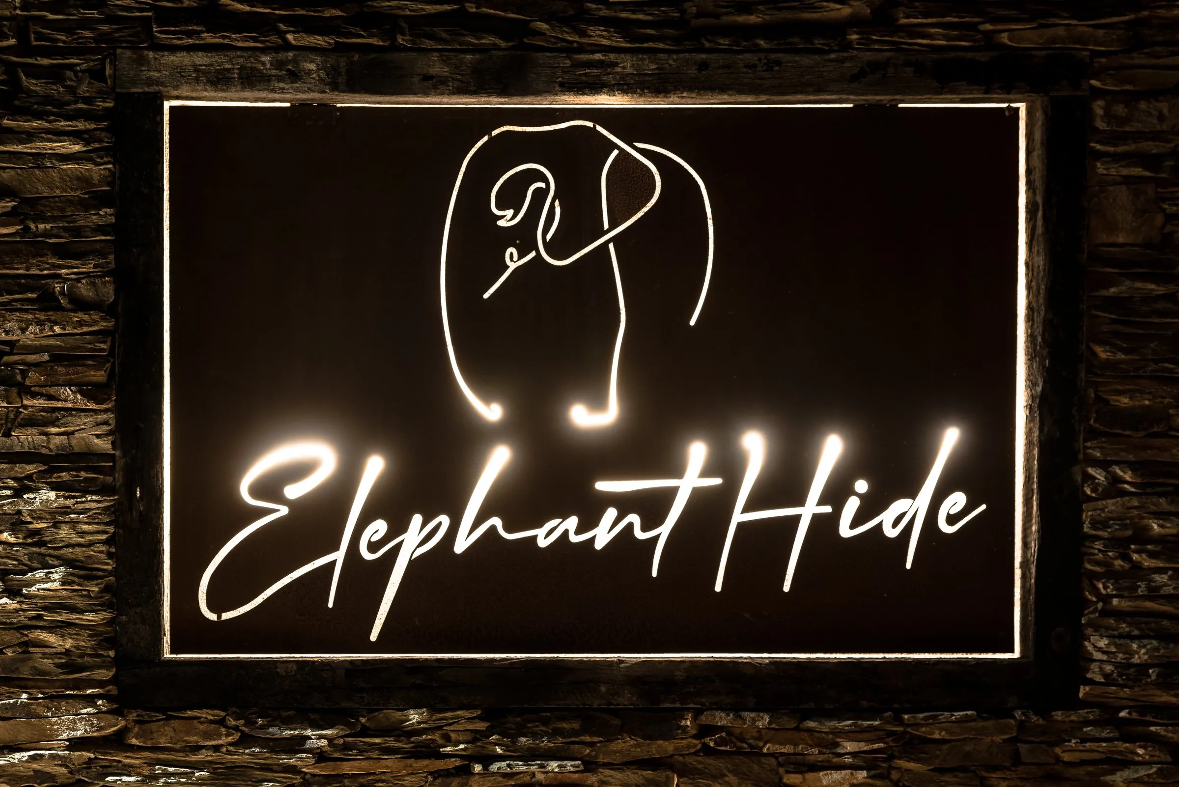 The Elephant Hide sign lit up at the lodge entrance at night