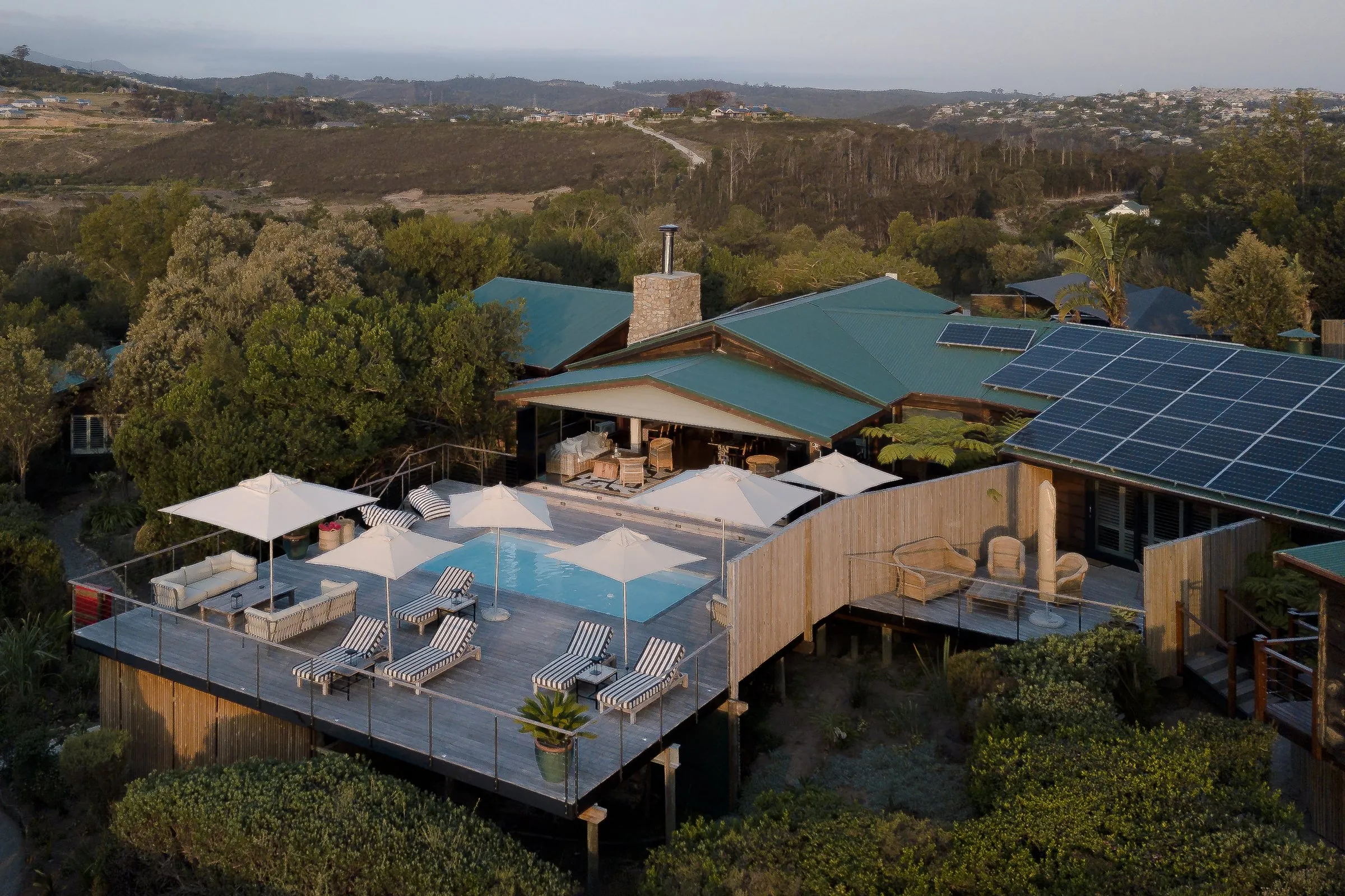 Aerial view of Elephant Hide: the pool deck, lodge and suites among indigenous trees on the hill above Knysna