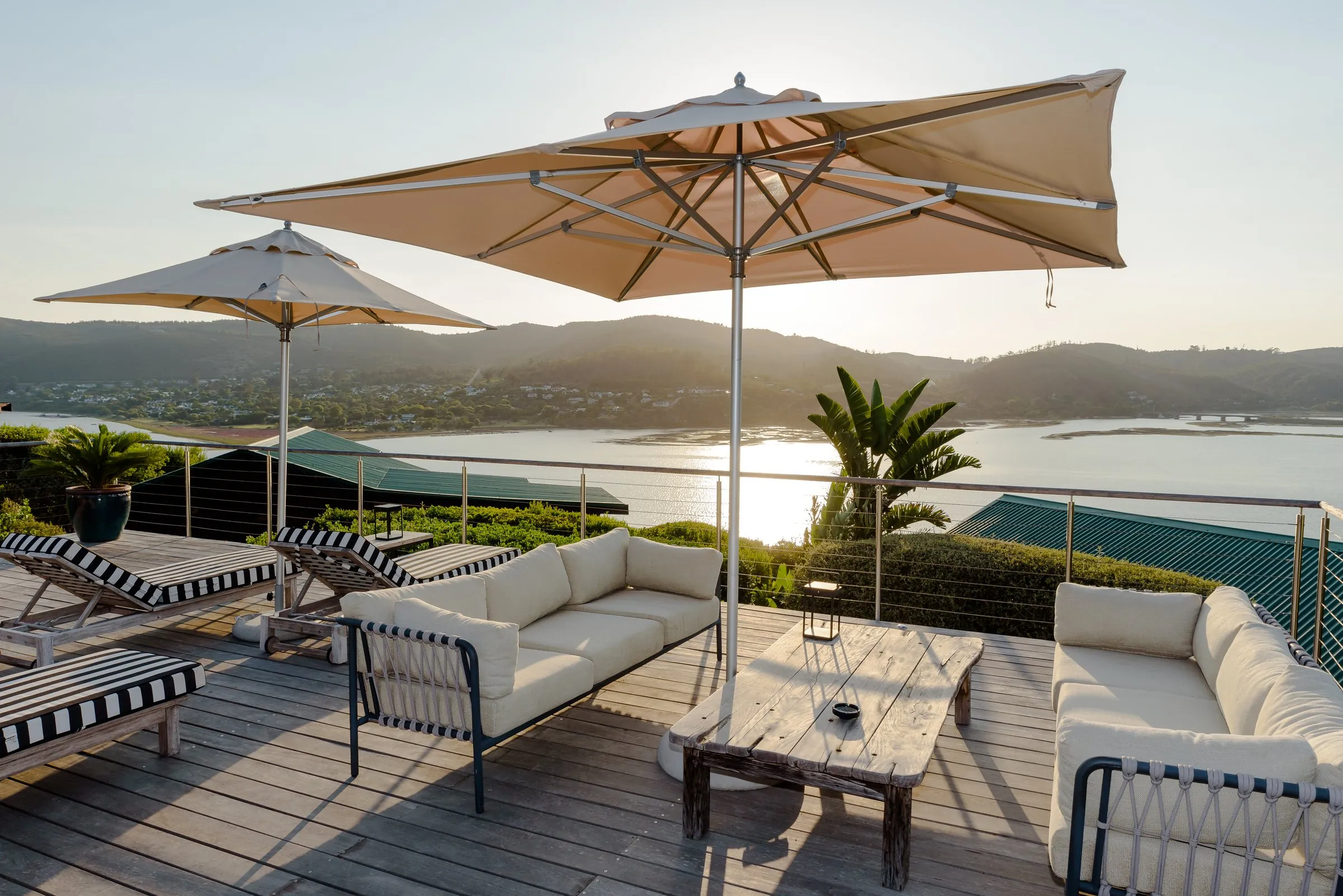 Loungers and umbrellas on the deck as the sun sets over the lagoon