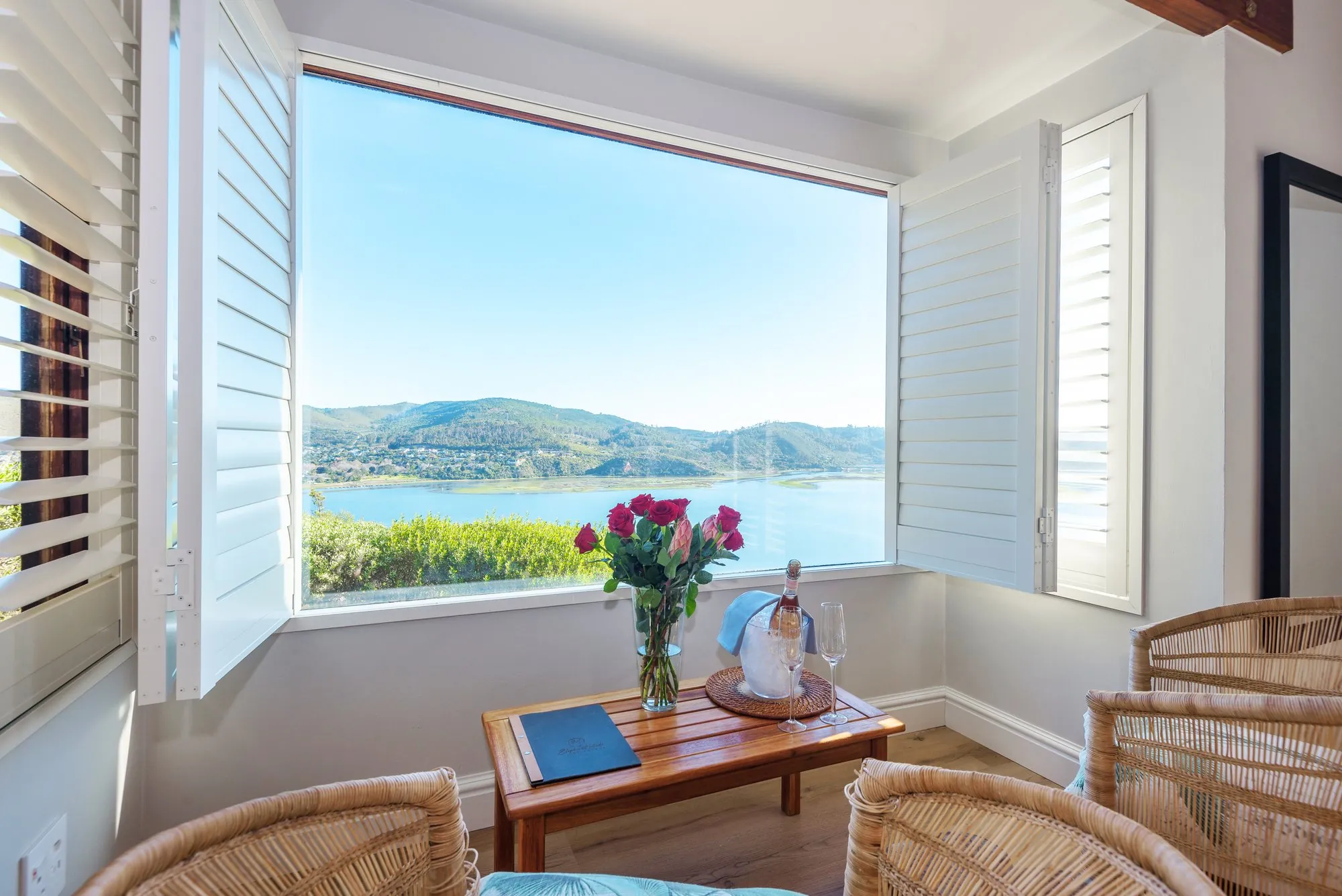 Wicker chairs and roses at a suite window above the lagoon