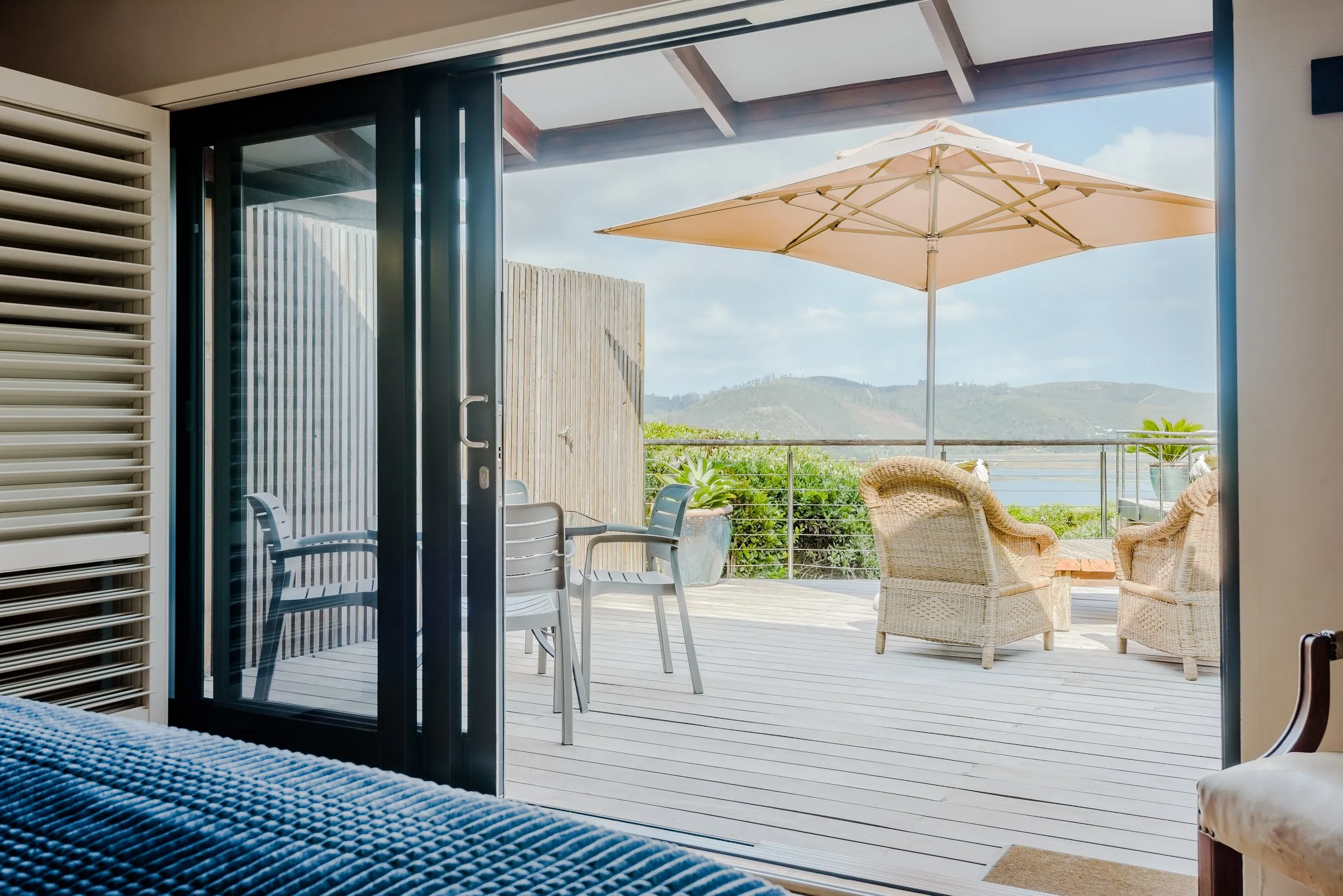 Family Suite bedroom opening onto a wooden deck with an umbrella and lagoon views