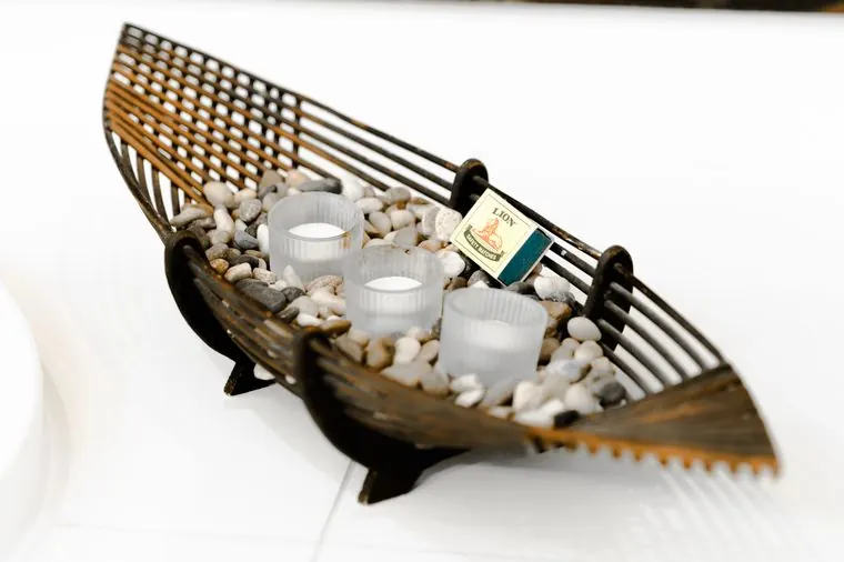 Candles in a carved boat on a bed of pebbles