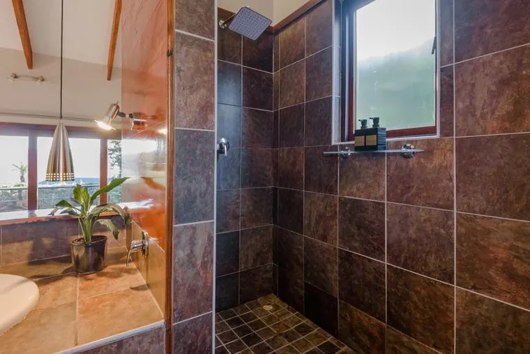 The waterfall shower in slate tiles, with a window to the trees