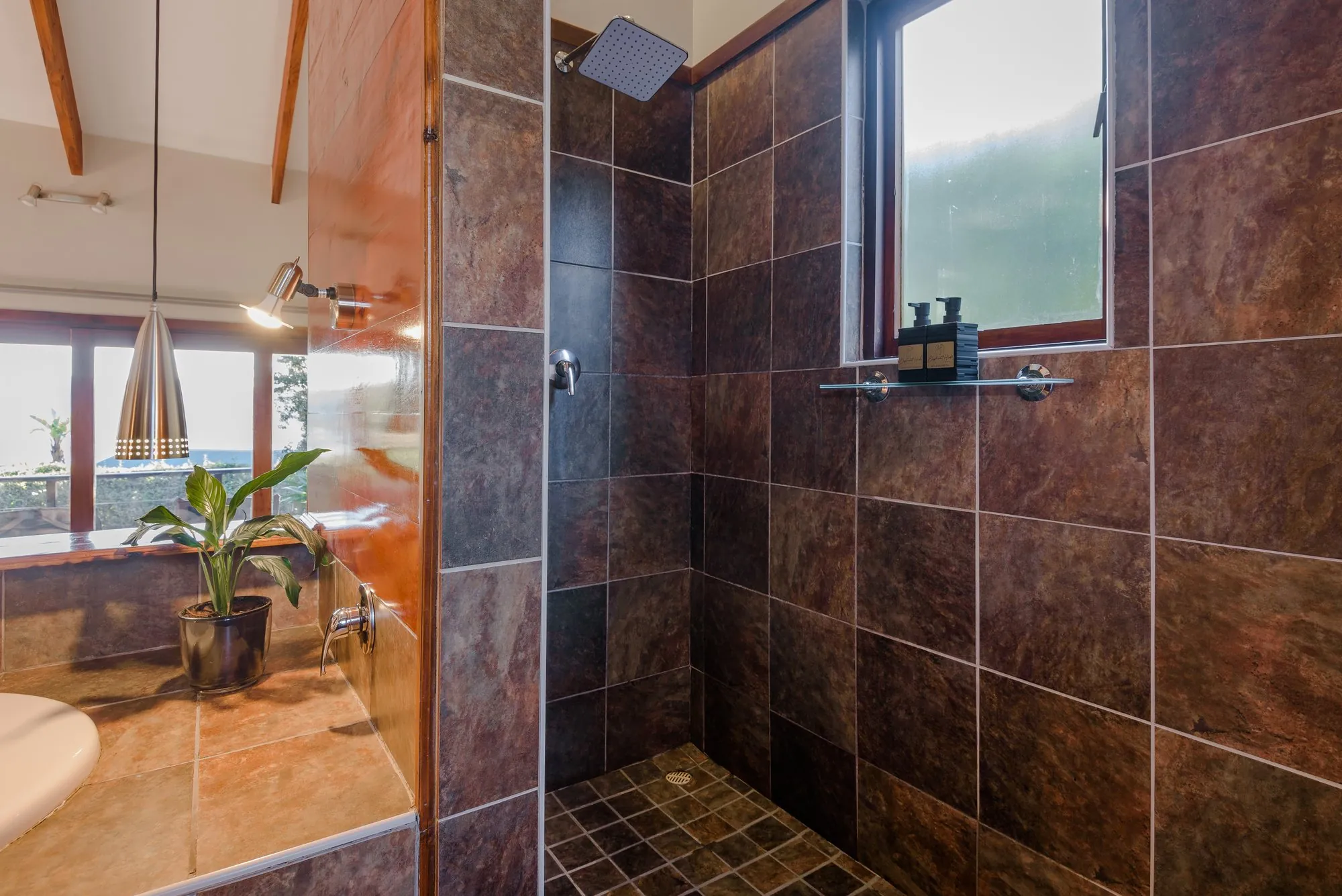 The waterfall shower in slate tiles, with a window to the trees