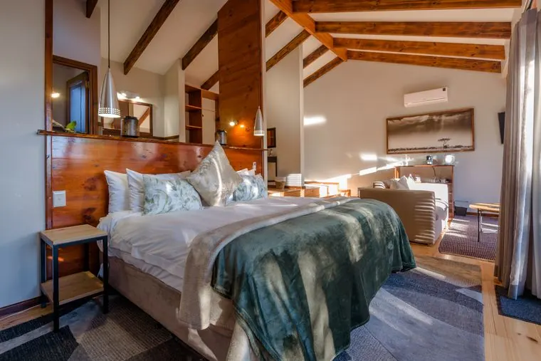 The bed with its timber headboard and a green throw