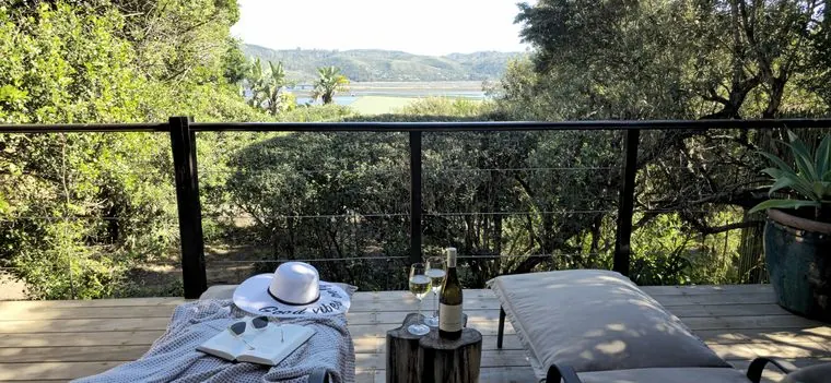 Loungers on the deck, looking through the trees to the lagoon