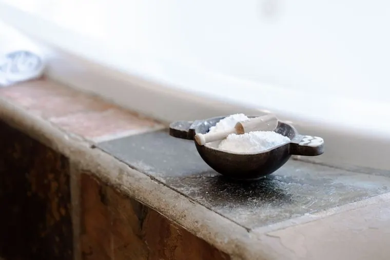 Bath salts in a bowl on the edge of the spa bath